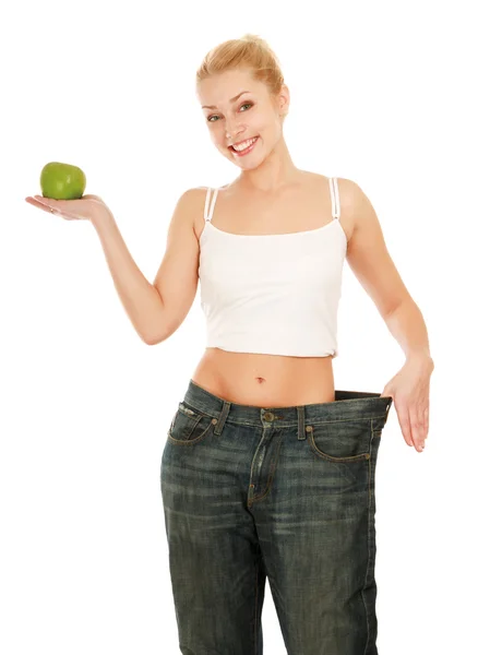Молодая девушка в больших джинсах и яблоке — стоковое фото