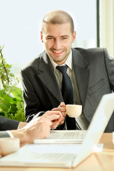 Een jonge man zit achter een laptop. — Stockfoto