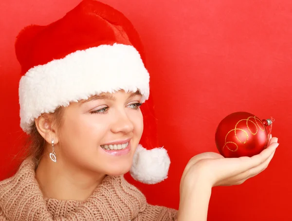 Kobieta na santa hat trzymając piłkę Bożego Narodzenia — Zdjęcie stockowe