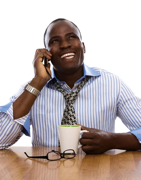 Afro homem sentado na mesa e falando ao telefone — Fotografia de Stock