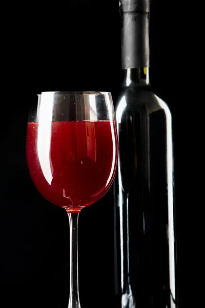 Copo de vinho tinto com uma garrafa — Fotografia de Stock