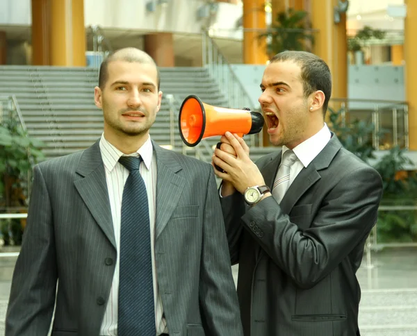 Två affärsmän, en med en högtalare som skriker — Stockfoto