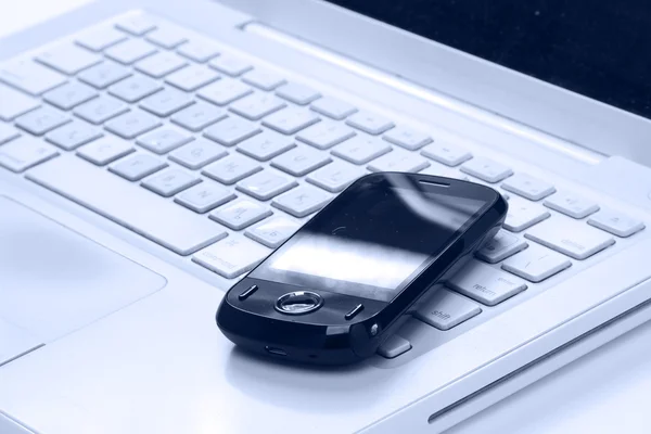 Telefone celular pelo teclado do laptop — Fotografia de Stock