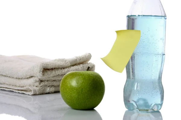 Towel, apple and bottle of water with yellow memo — Stock Photo, Image