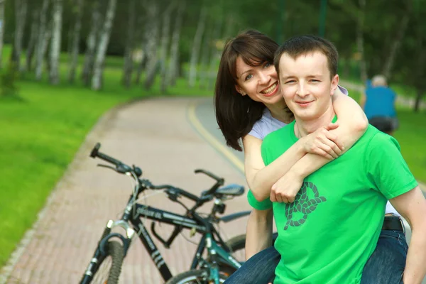 Woman riding bicycle outdoors with her husband — Stock Photo, Image