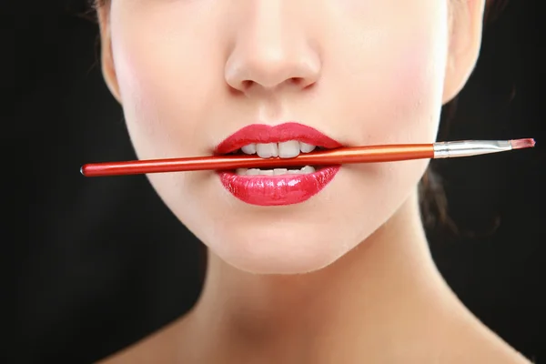 Lèvres de femme tenant la brosse à maquillage — Photo
