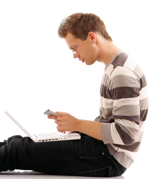 Ein Mann sitzt mit einem Laptop auf dem Boden Stockbild
