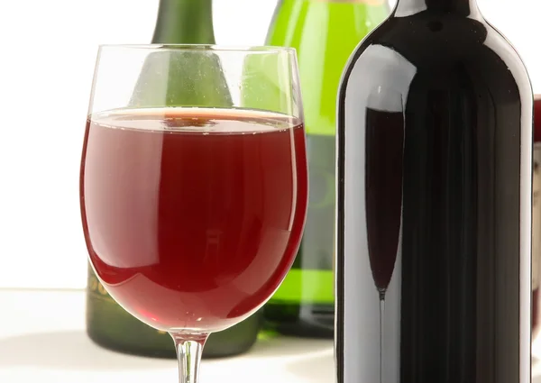 Copo de vinho tinto e garrafas de vinho — Fotografia de Stock