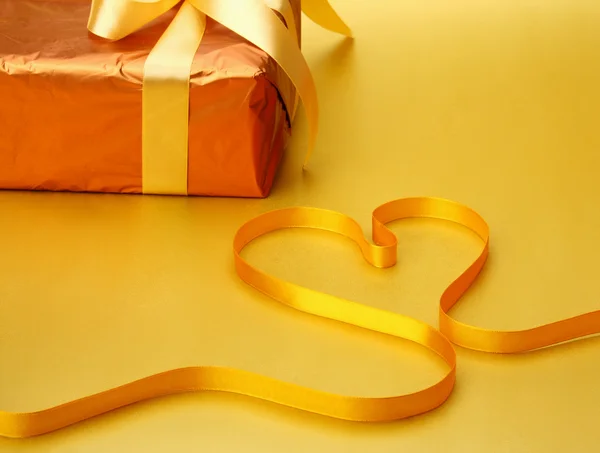 Gift and ribbon shaping heart — Stock Photo, Image