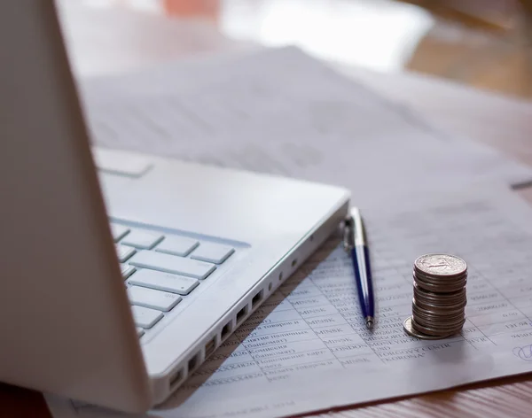 Mynt och pennan nära laptop — Stockfoto