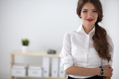 Ofiste kollarını kavuşturmuş çekici bir iş kadını.