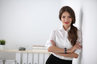 Ofiste kollarını kavuşturmuş çekici bir iş kadını.