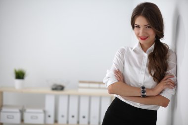 Ofiste kollarını kavuşturmuş çekici bir iş kadını.