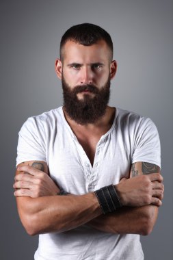 gri arka plan üzerinde izole çapraz kollu yakışıklı sakallı adam portresi