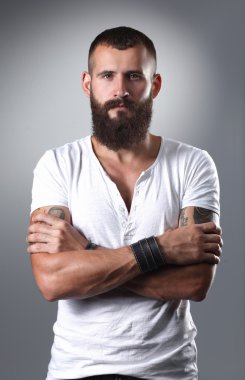 gri arka plan üzerinde izole çapraz kollu yakışıklı sakallı adam portresi