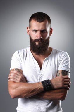 gri arka plan üzerinde izole çapraz kollu yakışıklı sakallı adam portresi