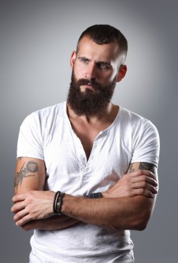 gri arka plan üzerinde izole çapraz kollu yakışıklı sakallı adam portresi