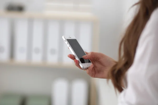 Zakenvrouw stuurt bericht met smartphone zittend op kantoor — Stockfoto