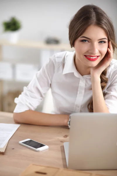 Aantrekkelijke zakenvrouw zit op het bureau in het kantoor — Stockfoto