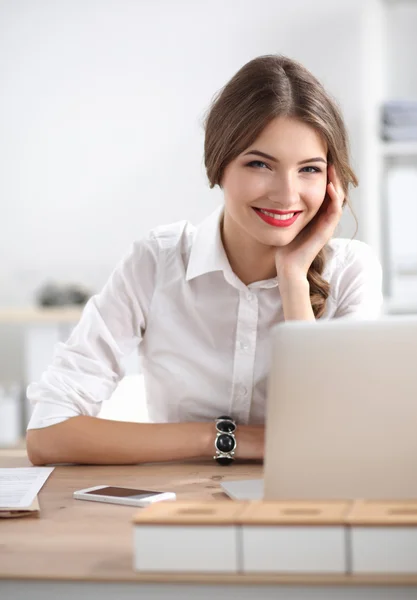 Attraktive Geschäftsfrau sitzt auf Schreibtisch im Büro — Stockfoto