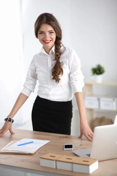 Attraente giovane donna d'affari in piedi vicino alla scrivania in ufficio — Foto Stock
