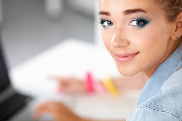 Portrait of young woman sitting on the desk with laptop in office — Stock Photo, Image