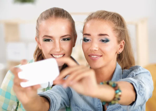 Zwei Mädchen, die zu Hause am Telefon Fotos machen — Stockfoto