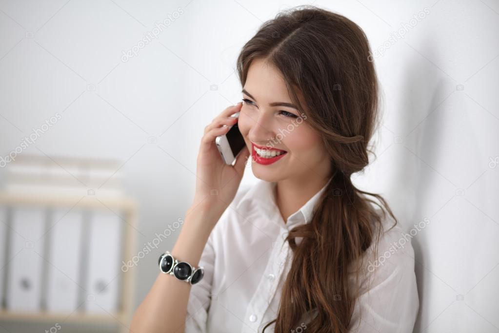 Smiling businesswoman talking on phone sitting at the office