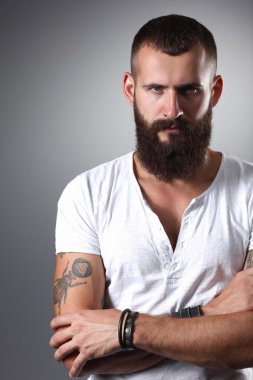 gri arka plan üzerinde izole çapraz kollu yakışıklı sakallı adam portresi