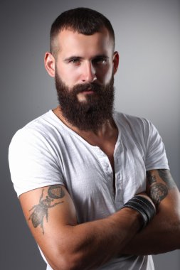 gri arka plan üzerinde izole çapraz kollu yakışıklı sakallı adam portresi