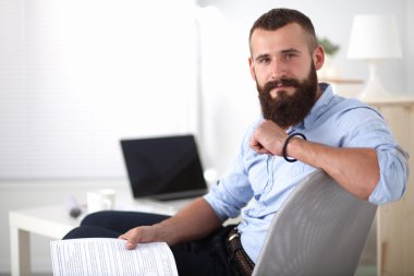 dizüstü bilgisayar ve bir çay bardağı evde oturan genç adam