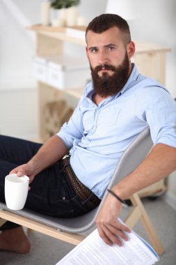 dizüstü bilgisayar ve bir çay bardağı evde oturan genç adam