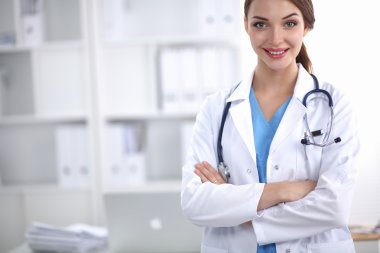 Portrait of young woman doctor with white coat standing in hospital clipart