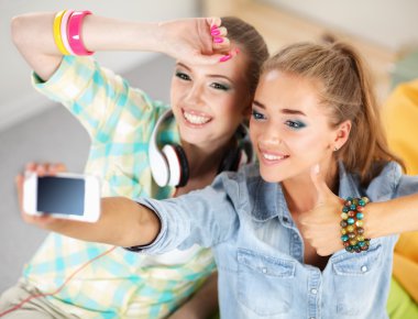 telefonda evde fotoğraf çekmek ve ok gösteren iki kız