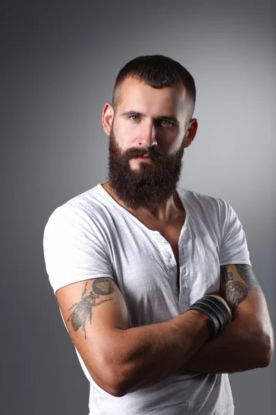 Portrait of handsome bearded man standing with crossed arms, isolated on grey background — Stock Photo, Image