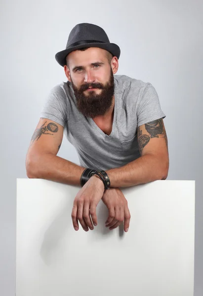 Retrato de un joven con sombrero de pie cerca del blanco, aislado sobre fondo blanco — Foto de Stock