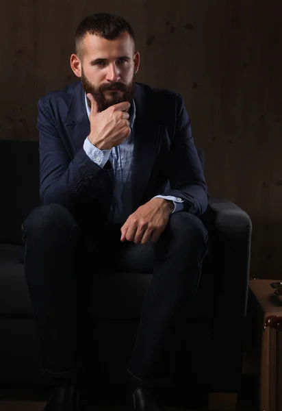 暗い背景に分離されたオフィスのロビーでソファーに座っている実業家 — ストック写真