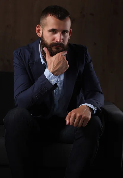 Geschäftsmann auf dem Sofa in der Büro-Lobby, isoliert auf dunklem Hintergrund — Stockfoto