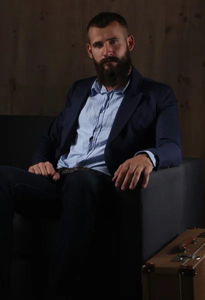 Businessman sitting the sofa in office lobby, isolated on dark background — Stock Photo, Image