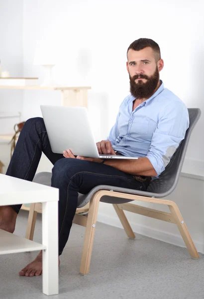 Hezký mladý muž sedí a pracuje na notebooku. — Stock fotografie