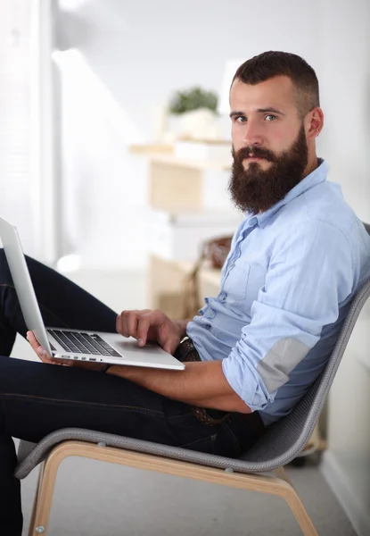 Bello giovane seduto e al lavoro sul computer portatile. — Foto Stock