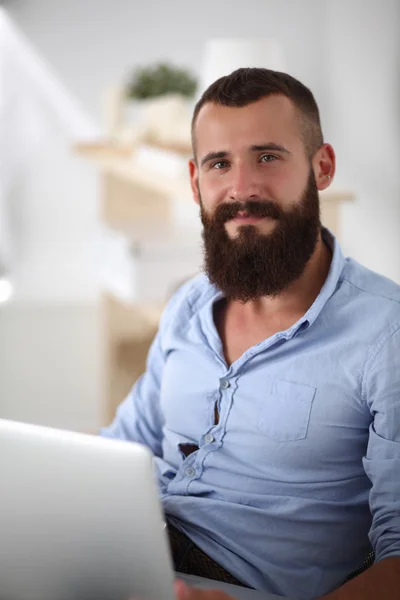 Handsome young man sitting and working on laptop computer. — Stock Photo, Image