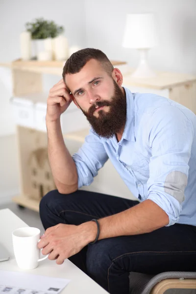 Jonge man zittend met laptop en een kopje thee thuis — Stockfoto