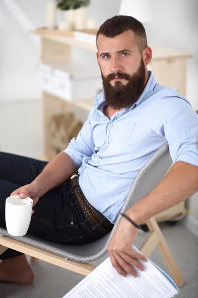 Hombre joven sentado con el ordenador portátil y una taza de té en casa —  Fotos de Stock