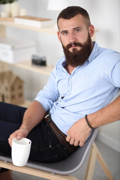 Hombre joven sentado con el ordenador portátil y una taza de té en casa —  Fotos de Stock