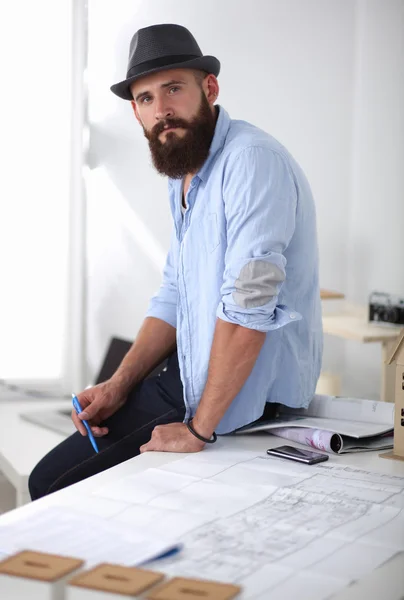 Portret van mannelijke ontwerper in hoed met blauwdrukken aan balie — Stockfoto