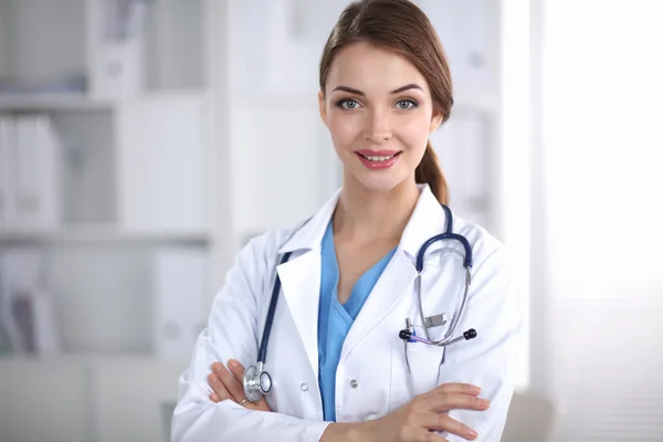 Retrato de una joven doctora con una bata blanca de pie en el hospital —  Fotos de Stock