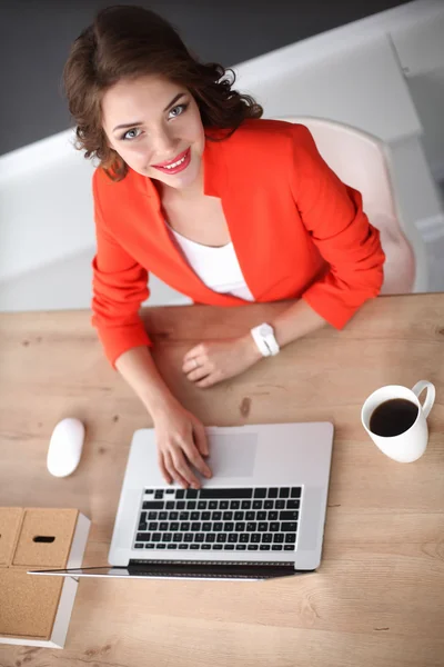 Mujer atractiva sentada en el escritorio en la oficina, trabajando con el ordenador portátil —  Fotos de Stock