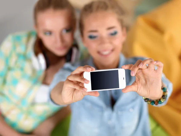 Zwei Mädchen, die zu Hause am Telefon Fotos machen — Stockfoto