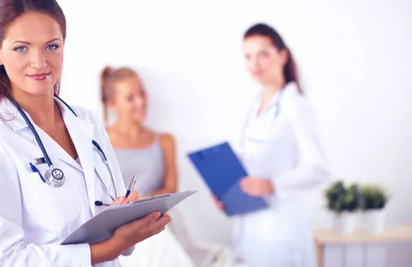 Sorridente medico donna con una cartella in uniforme in piedi a tubo flessibile — Foto Stock